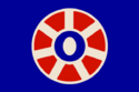 Cobalt blue flag, with seven equidistant and equally sized red trapezoids on a white circle surrounding a white oval.
